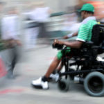 Man using electric wheelchair on sidwalk