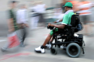 Man using electric wheelchair on sidwalk