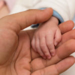 Adult holding infant's hand
