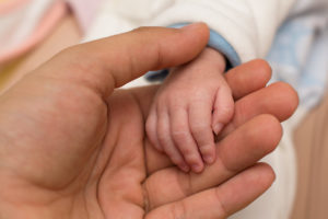 Adult holding infant's hand