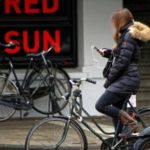 Young woman texting and biking