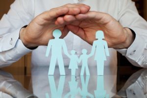 Man placing hands over paper family