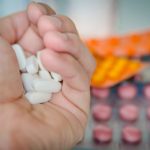 Hand holding white pills