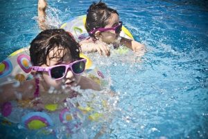 Girls wearing sunglasses are swimming in the pool