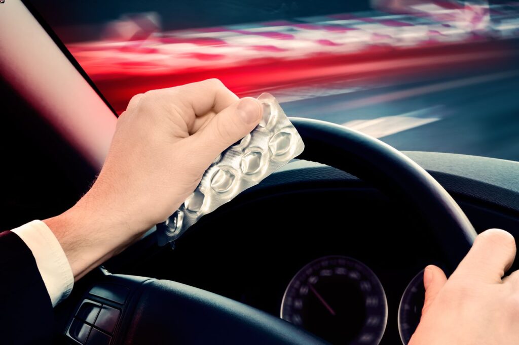 Man drivers a car while holds a medication