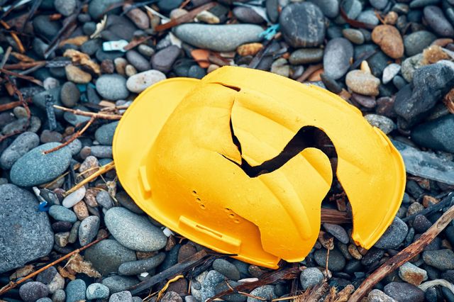 A broken yellow hardhat on ground